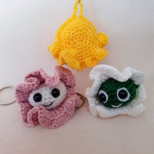 Heklani privezak u obliku školjke sa biserom i osmehom, pričvršćen za metalni prsten Prikazane su tri školjkice u beloj, roze i žutoja boji.