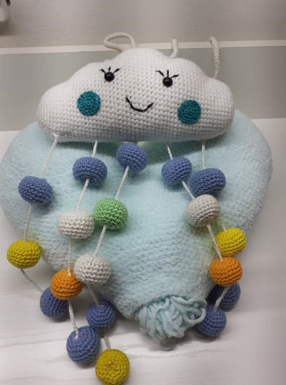 Detalj o tome šta je amigurumi. Jastuk u obliku srca i oblk iz kojeg vise zvečke.